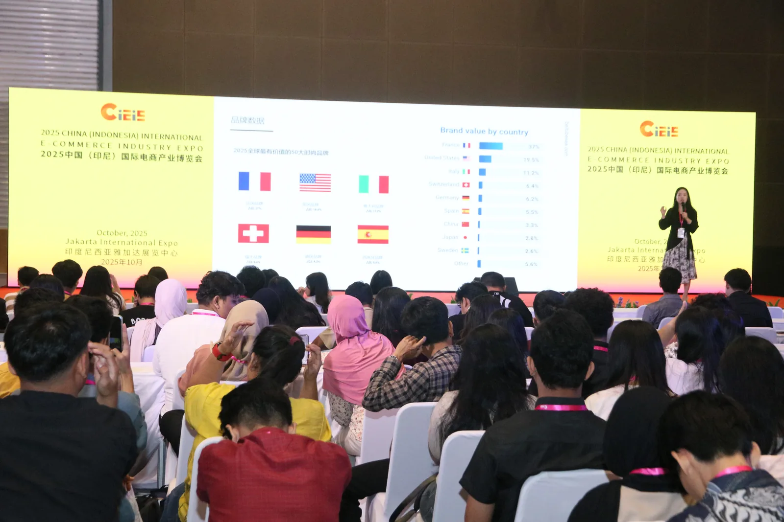 Booth pameran dengan display produk dan pengunjung berdiskusi